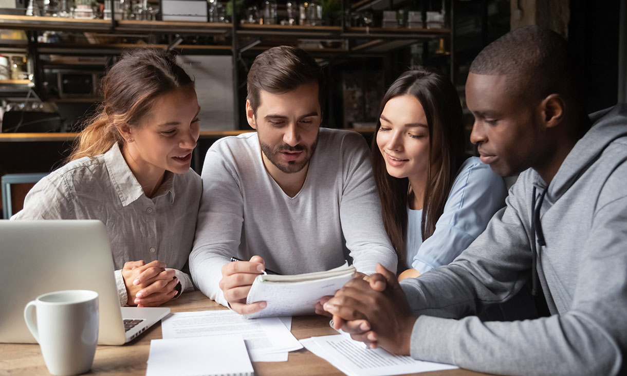Stock image: Four students looking down at paper interacting