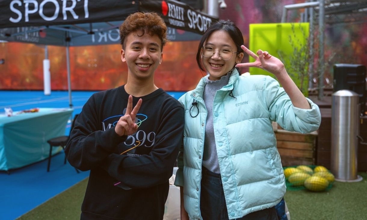 Two students smiling for photo, actioning the peace sign