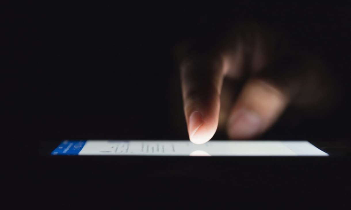 Stock image: Finger scrolling on smartphone in the dark