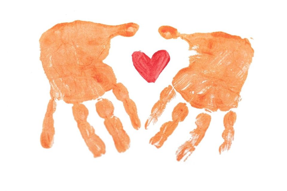 Two painted hand prints in orange with a love heart print between