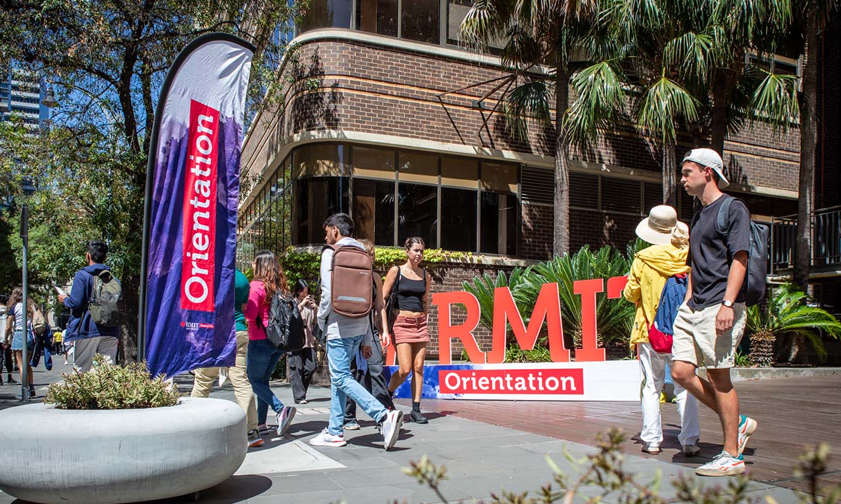University students walk in front of promotional signage.