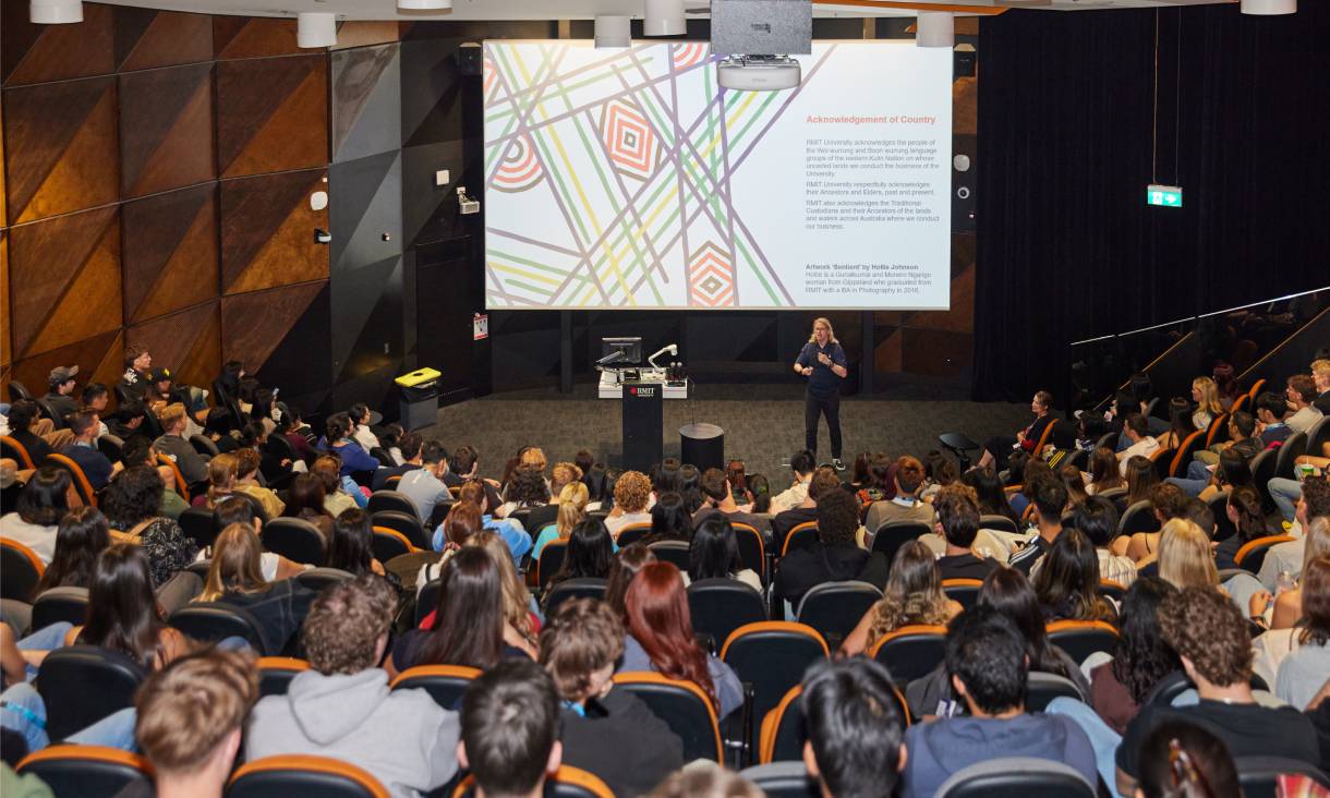 Person presenting to full lecture theatre with projector