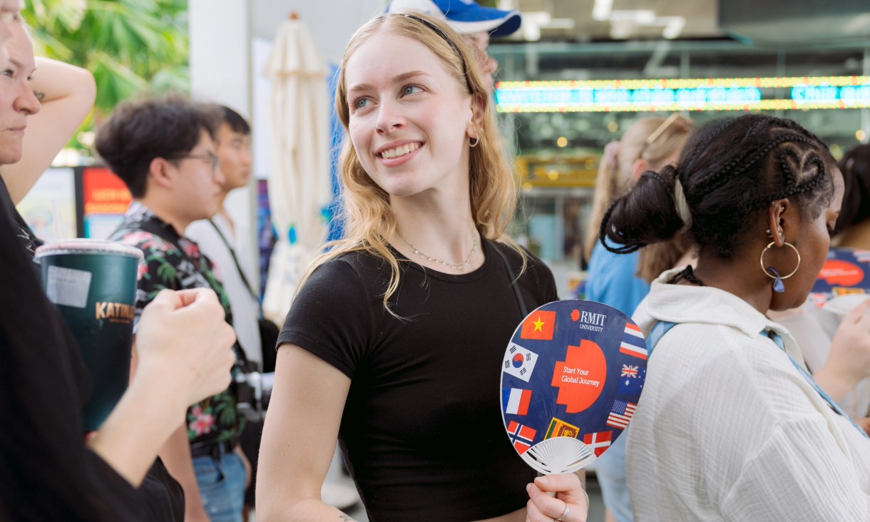 Student smiling holding a fan adorned with flags
