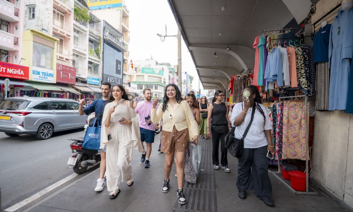 A group of people walk through a market Ho Chin Minh City, Vietnam.