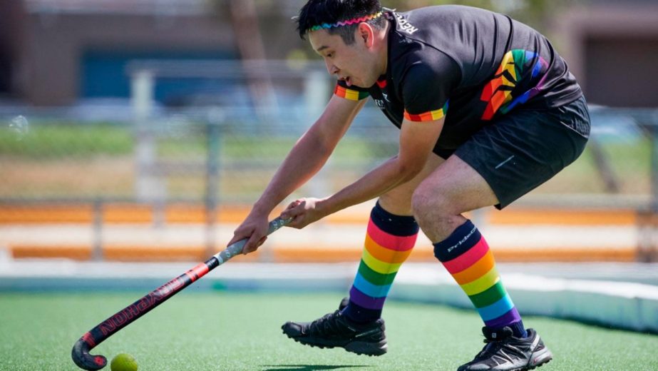 Student in pride rainbow socks playing hockey