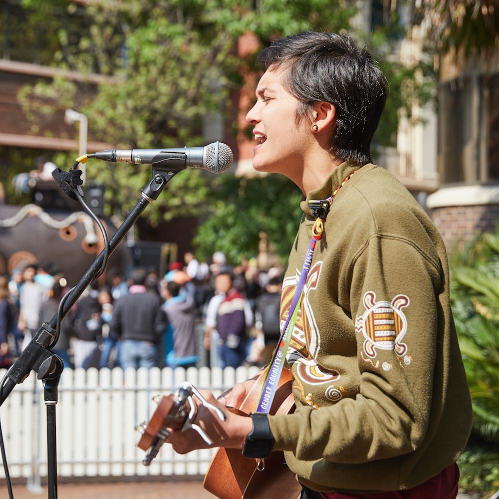 A singer with a guitar performs on campus.