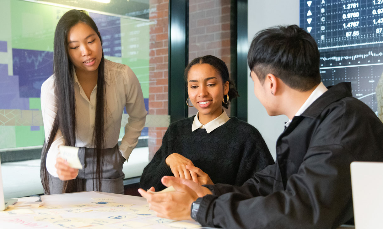 Three RMIT business students working on a group project using sticky notes to share ideas