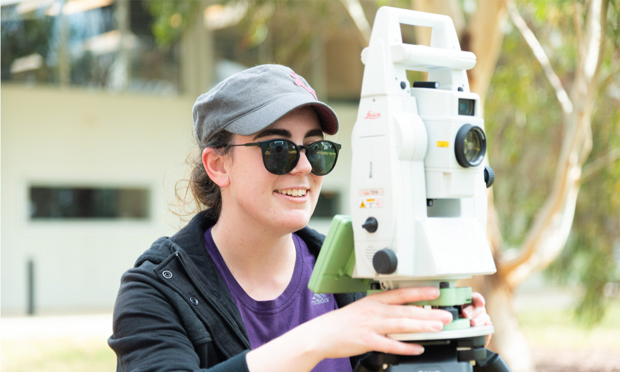 RMIT student using a piece of surveying equipment in the field