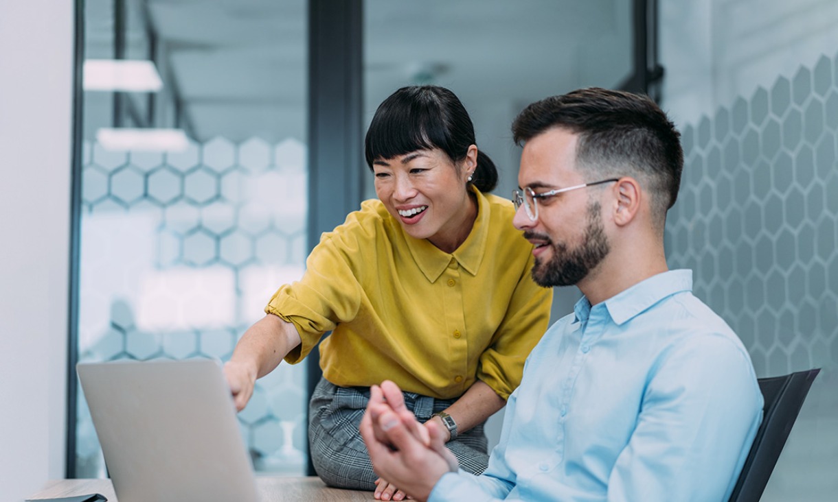 Two people looking at laptop smiling. 