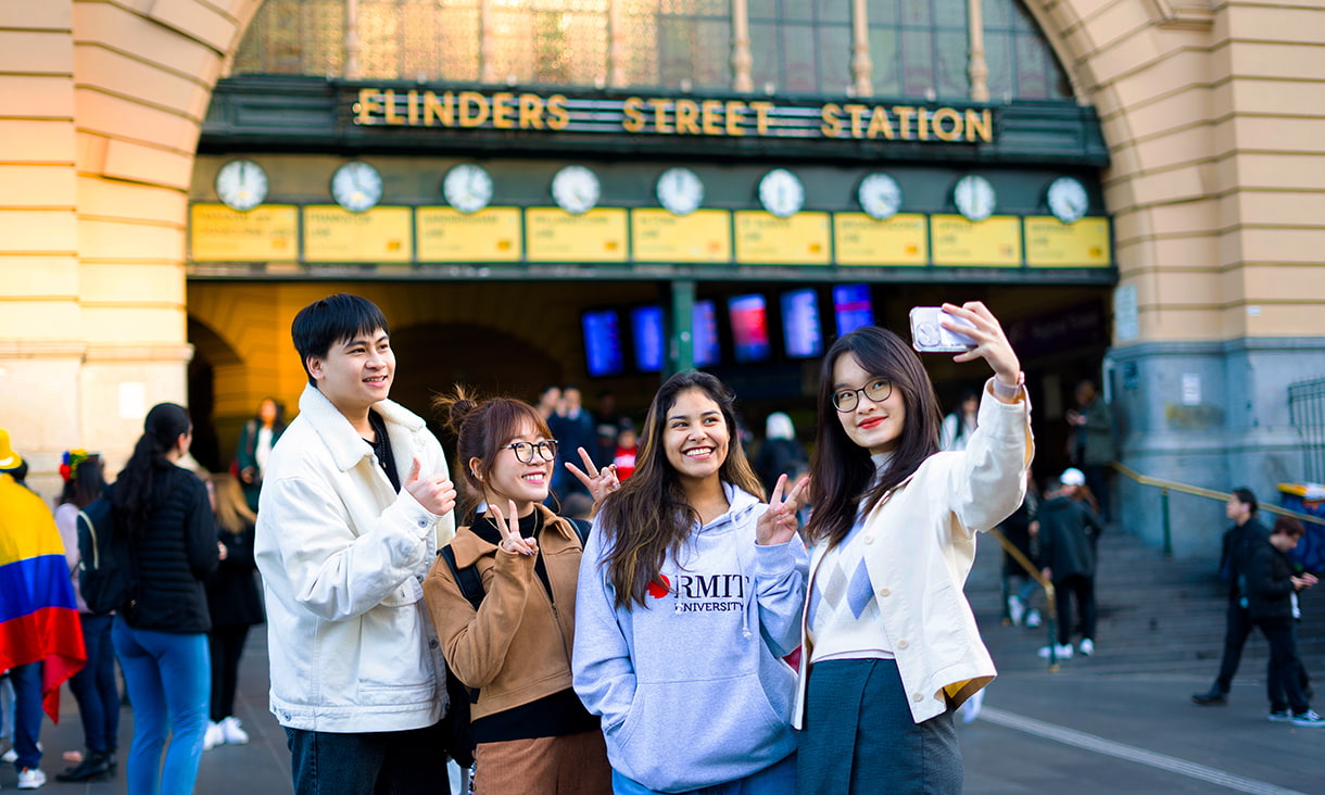 Four international students taking a selfie outside Flinders St Station.