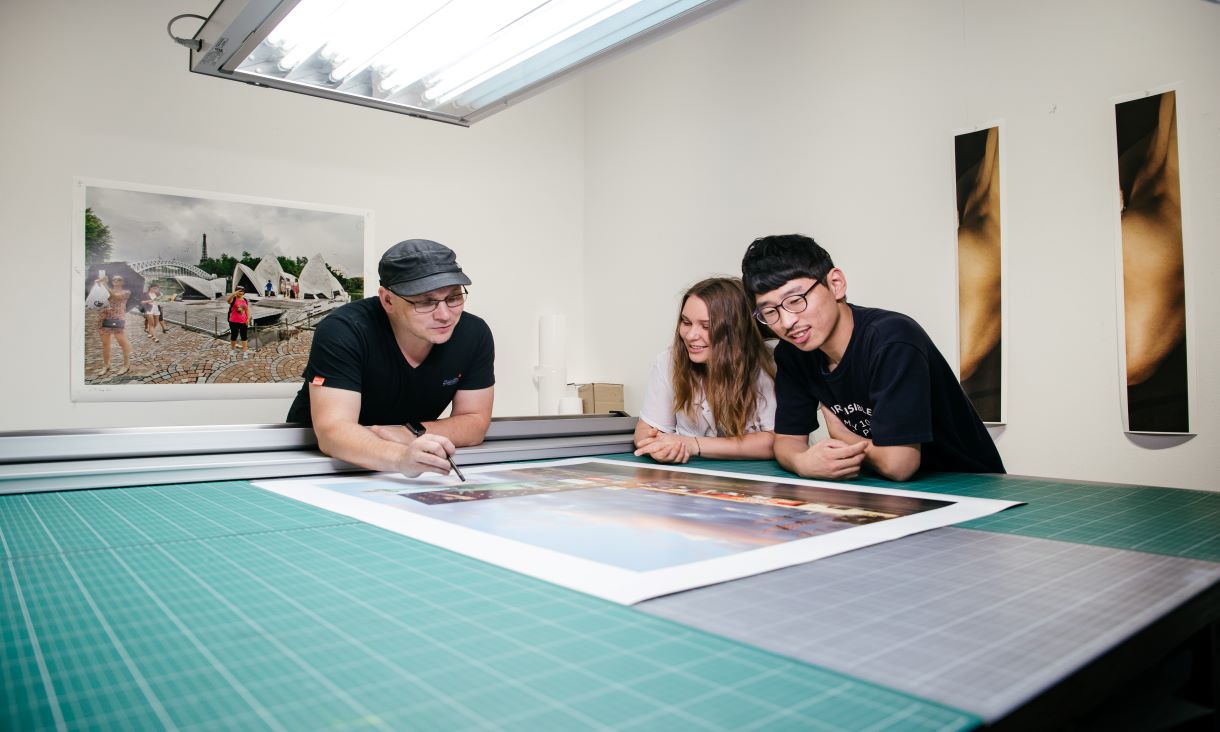 Three students examining large photo print on table