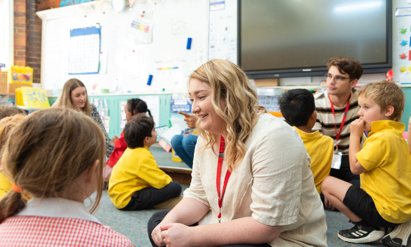An RMIT education student sitting in a classroom with primary school students