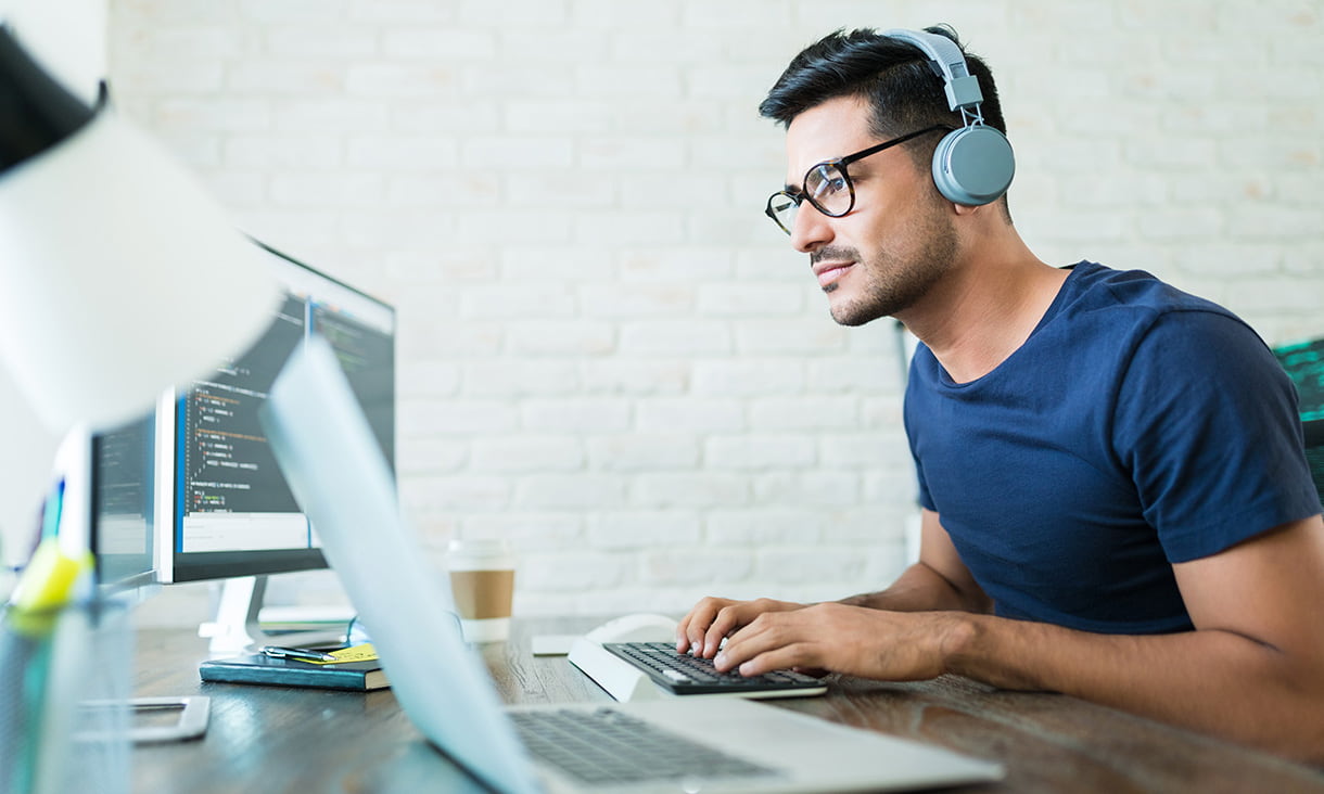 Male wearing headphones as he uses his computer