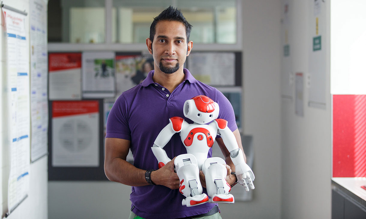 Man stands holding red and white robot