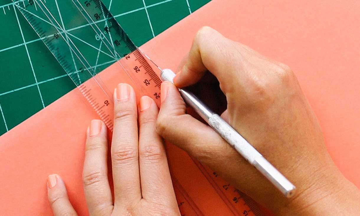 Hands cutting paper card with ruler