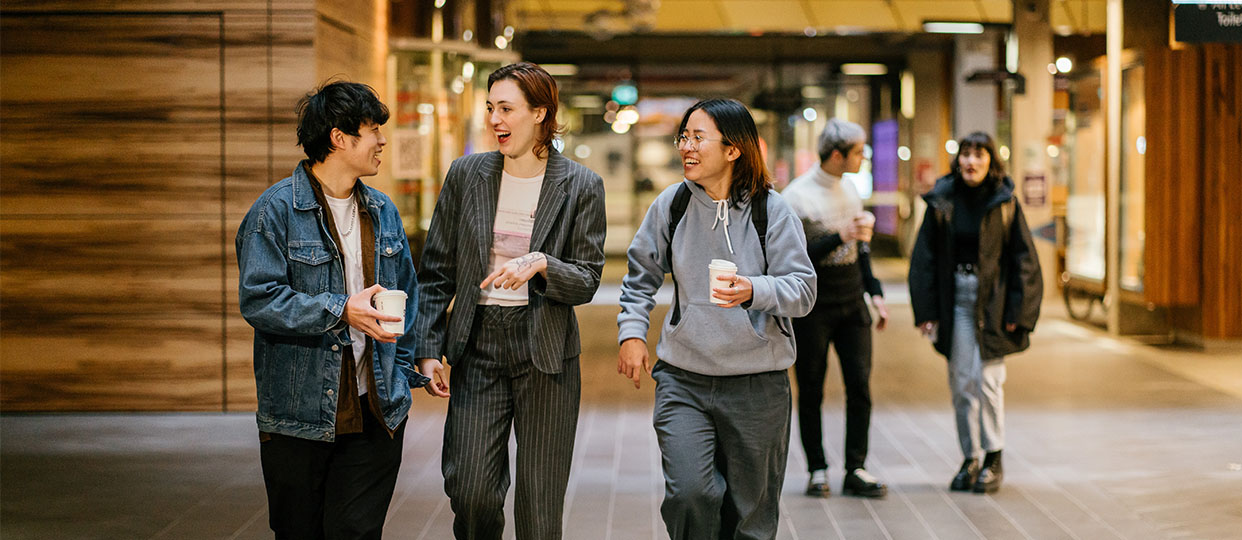 Three students walking with coffee at the RMIT Melbourne City campus