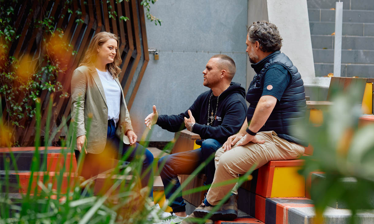 Three RMIT social work students sitting and discussing on a set of colourful steps