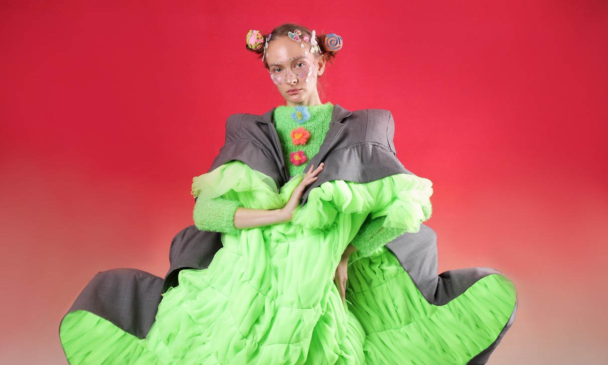 Fashion design model wearing green puffy dress with flower detail and lapeled grey jacket.Photo credit: Rebecca Li, Fashion Design Persona Project, 2021. Photography by Nirvana Wu, styling by Guanqun, model - Alina.
