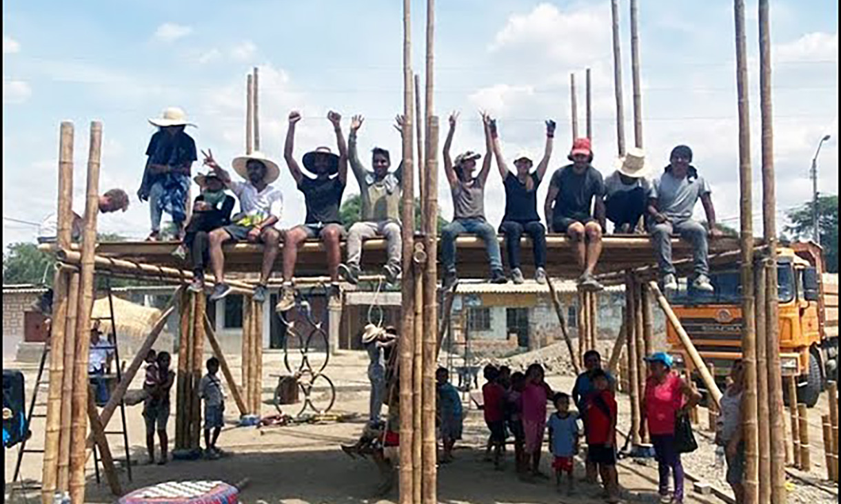 Students sitting on scaffolding with their arms raised