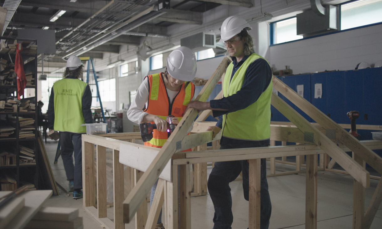 Danielle, Diploma of Building and Construction student, using a drill on a mock building site