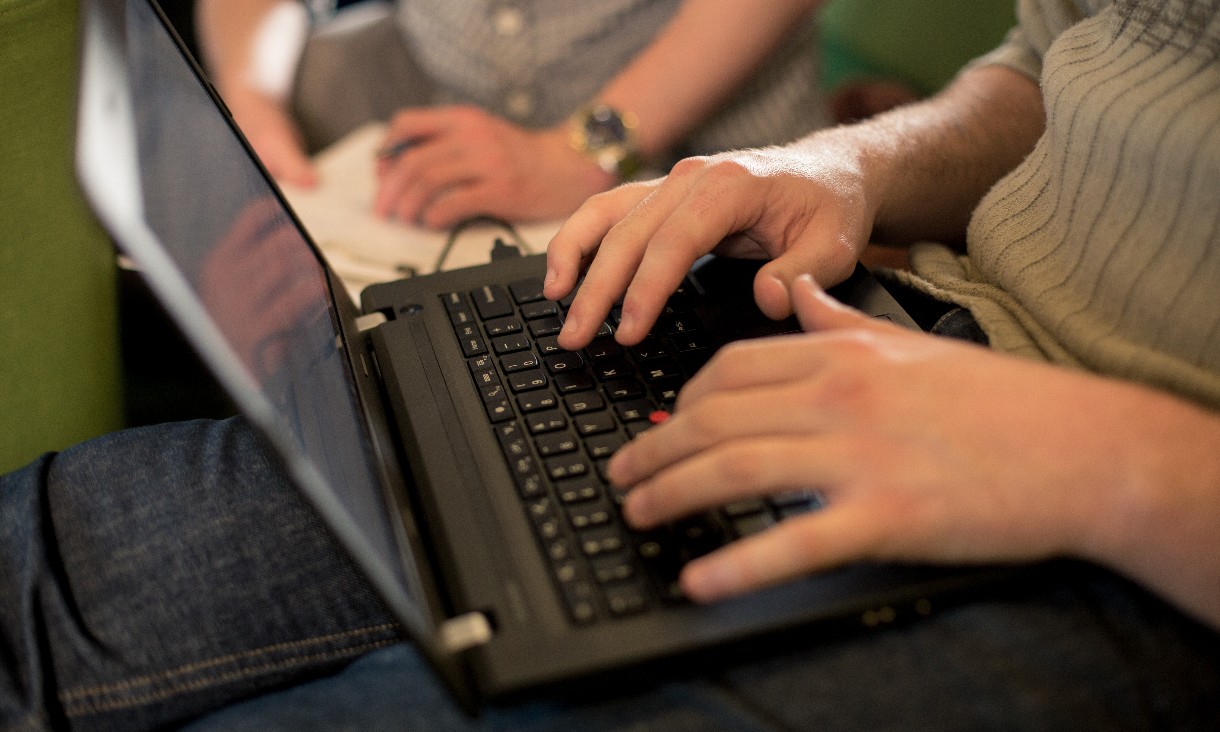 A close-up shot of a laptop and two hands on the keyboard
