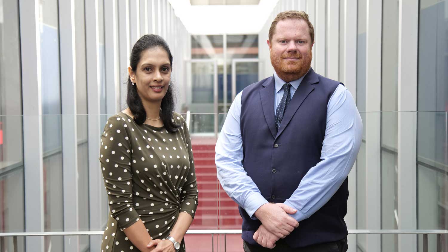 Photo of Dr Mahi Narayanan and Dr Bradley McConachie standing on a balcony, staircase in background