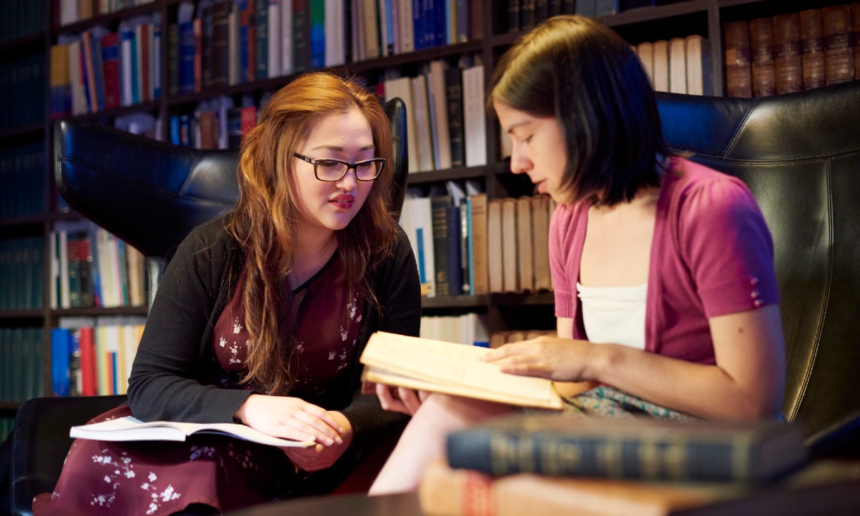 two female students looking at book in the Law library