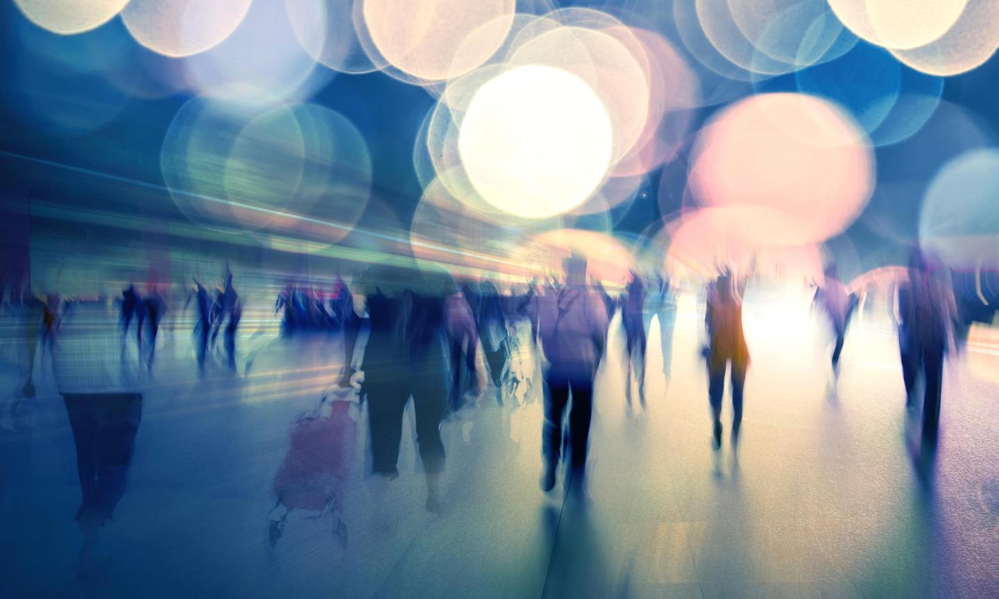 Many people walking in an artistically colourful and blurred image