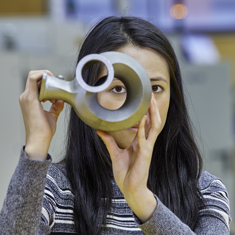 Female student holding metal object up to eye