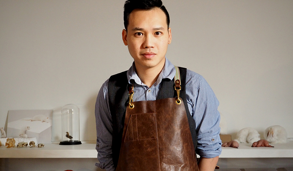 Male student, wearing a leather apron, looking towards the camera