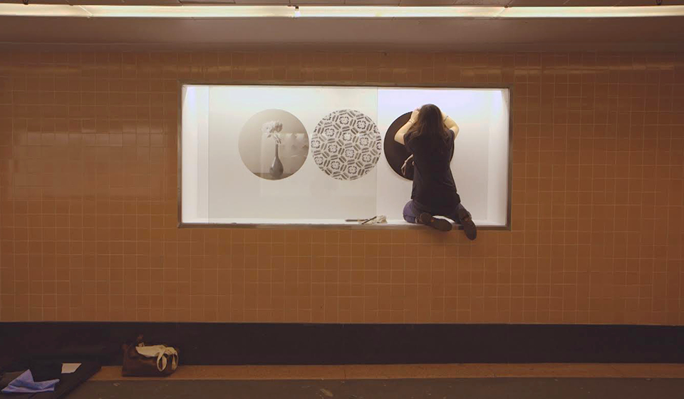 Art installation on a wall; student placing a piece inside an inset part of the wall