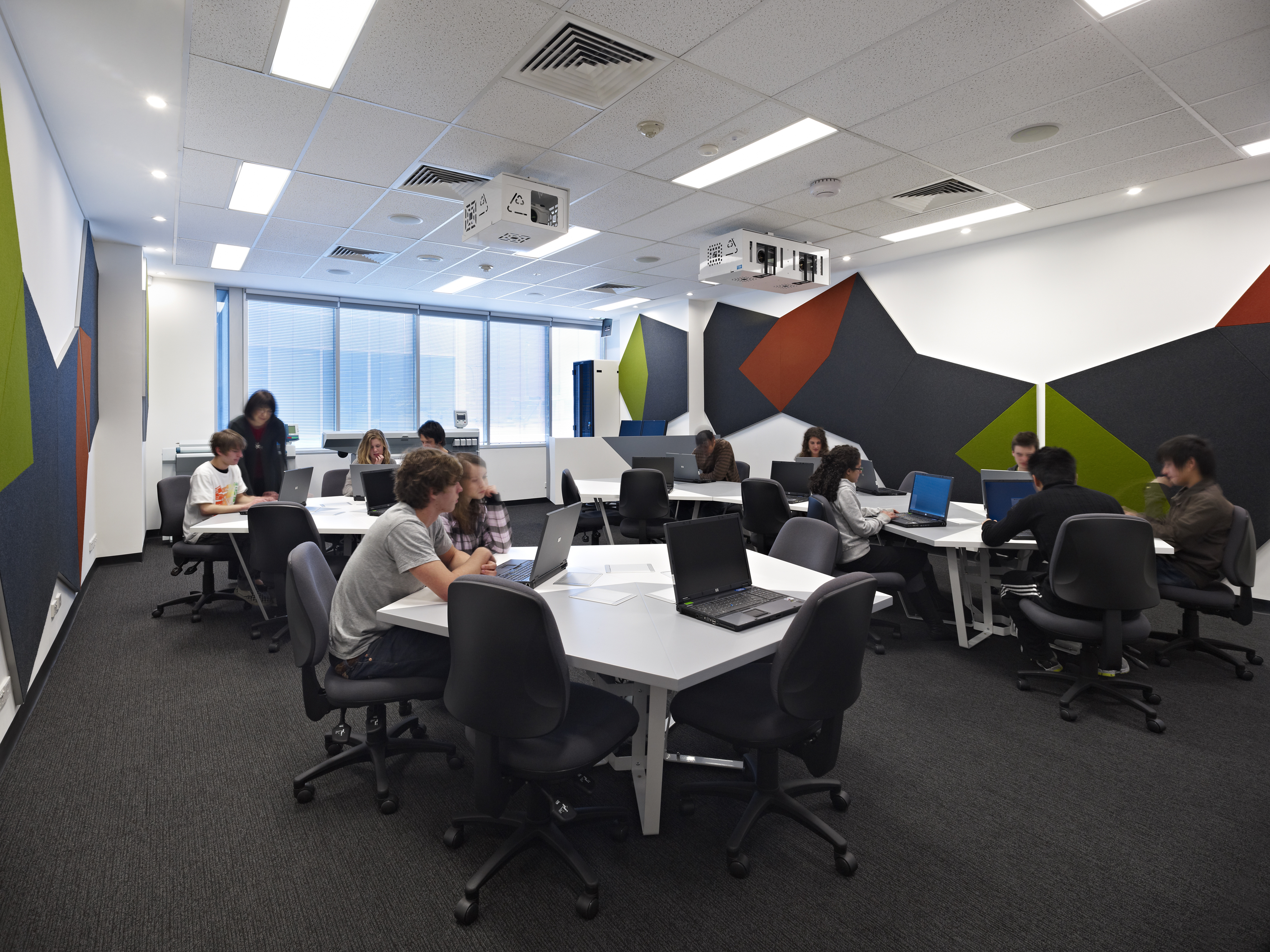 A wide shot of a classroom setting inside an RMIT building with students sitting at desks, working on laptops