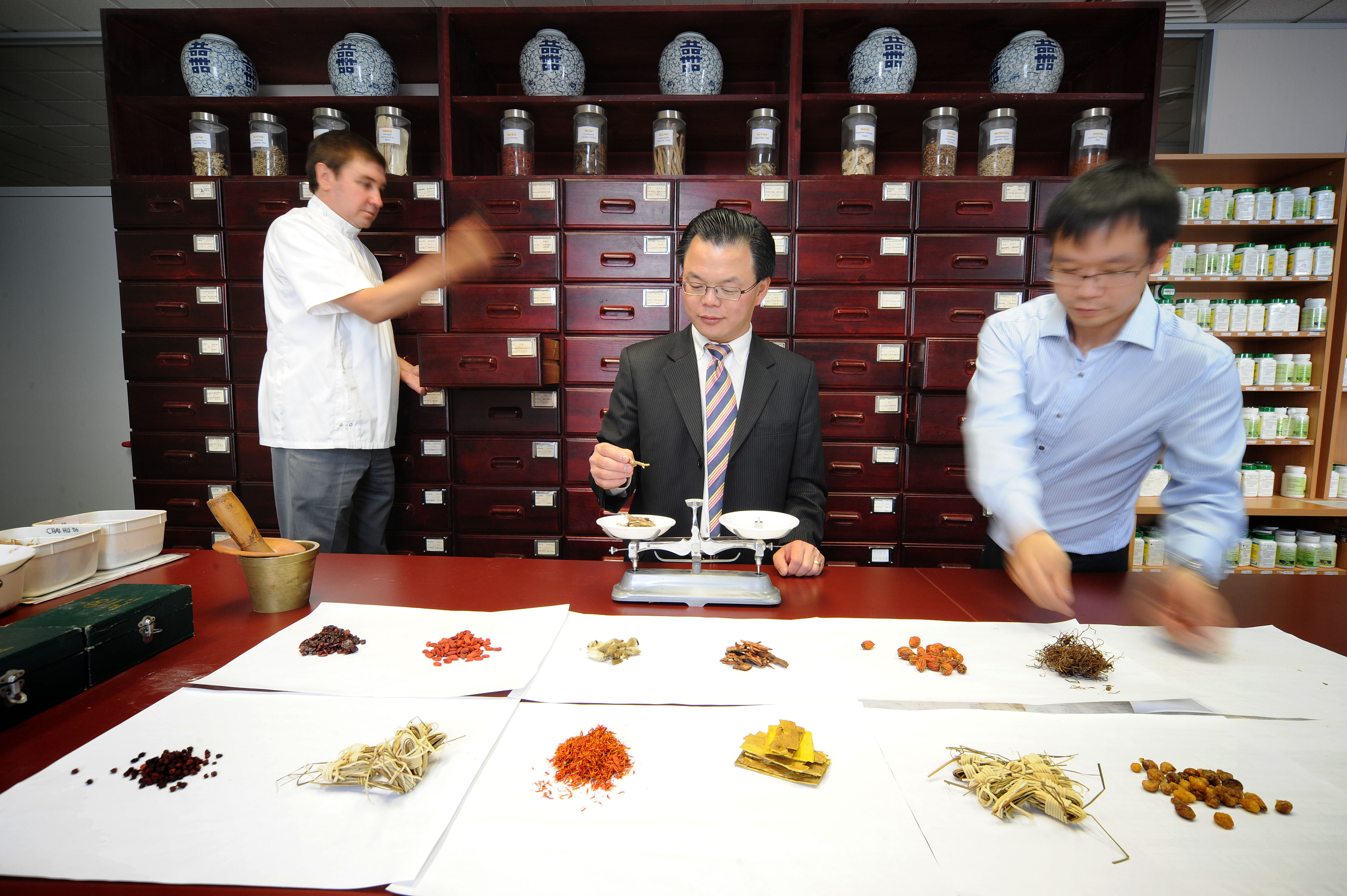 researchers weighing various herbs on a set of scales