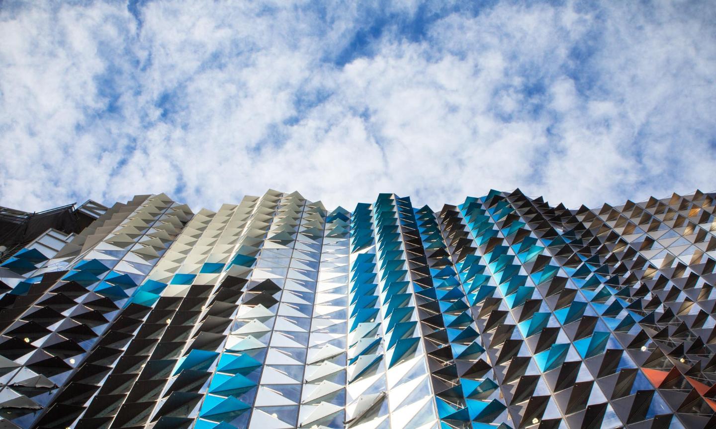 abstract photo of a mirrored building with blue sky and clouds above.