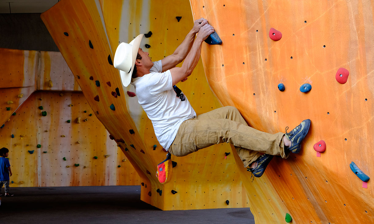 Stuart Beekmeyer hanging from an indoor rock climbing traverse wall.