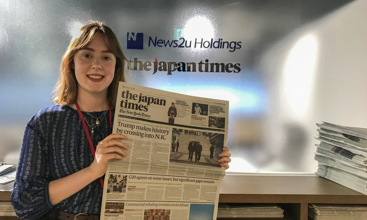 Rachel Merritt holding a copy of The Japan Times featuring one of her published articles.
