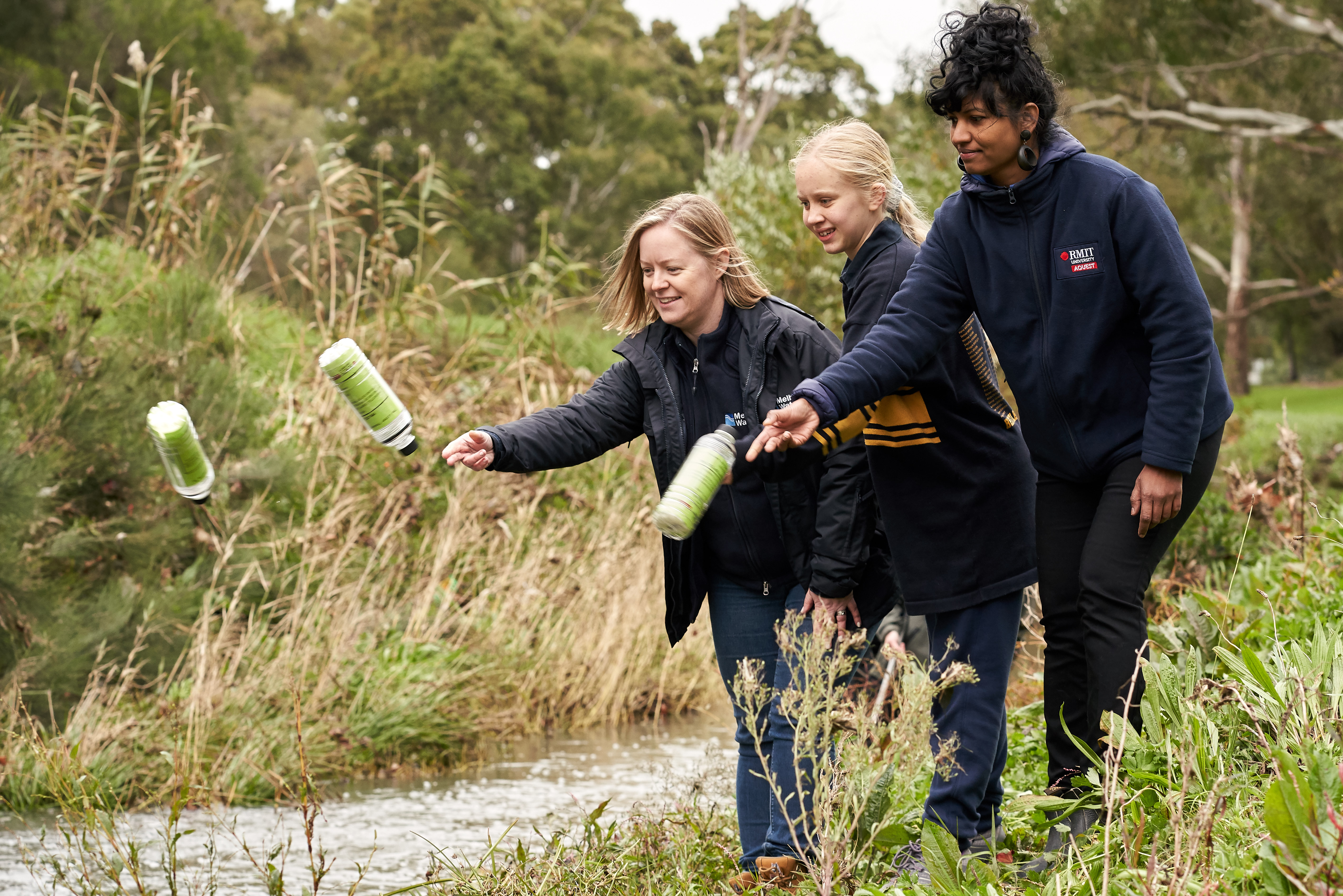 Melbourne Water’s Litter and Waterwatch Coordinator Naomi Dart, citizen scientist and Bentleigh West Primary School student Sophie Littlefair and RMIT’s Dr Kavitha Chinathamby launching GPS-tracked bottles into Dandenong Creek.