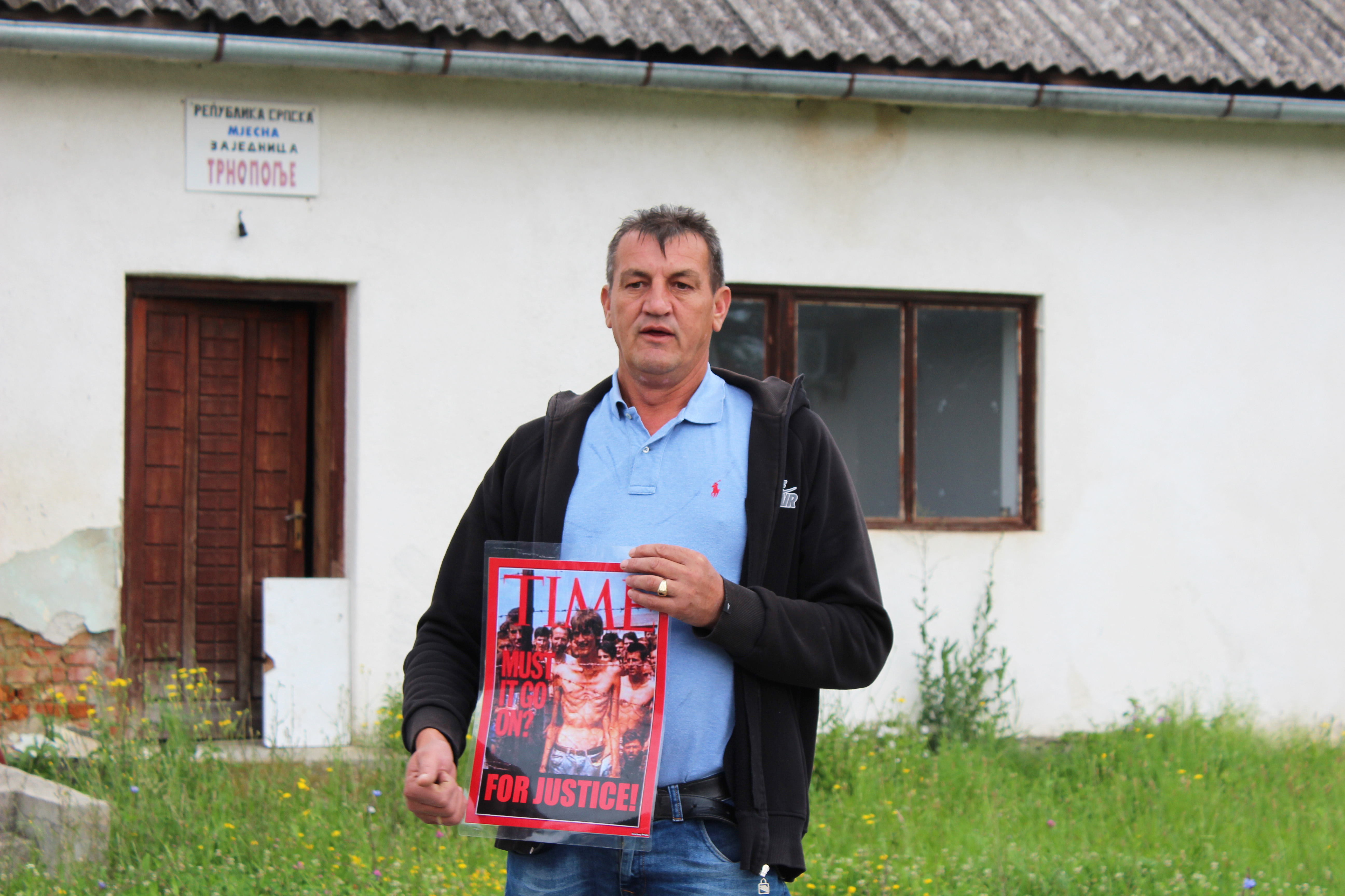 Fikret Alic shows the group a copy of Time magazine from 1992 with himself on the cover during a tour of the Trnopolje concentration camp near Prijedor, Bosnia and Herzegovina. 