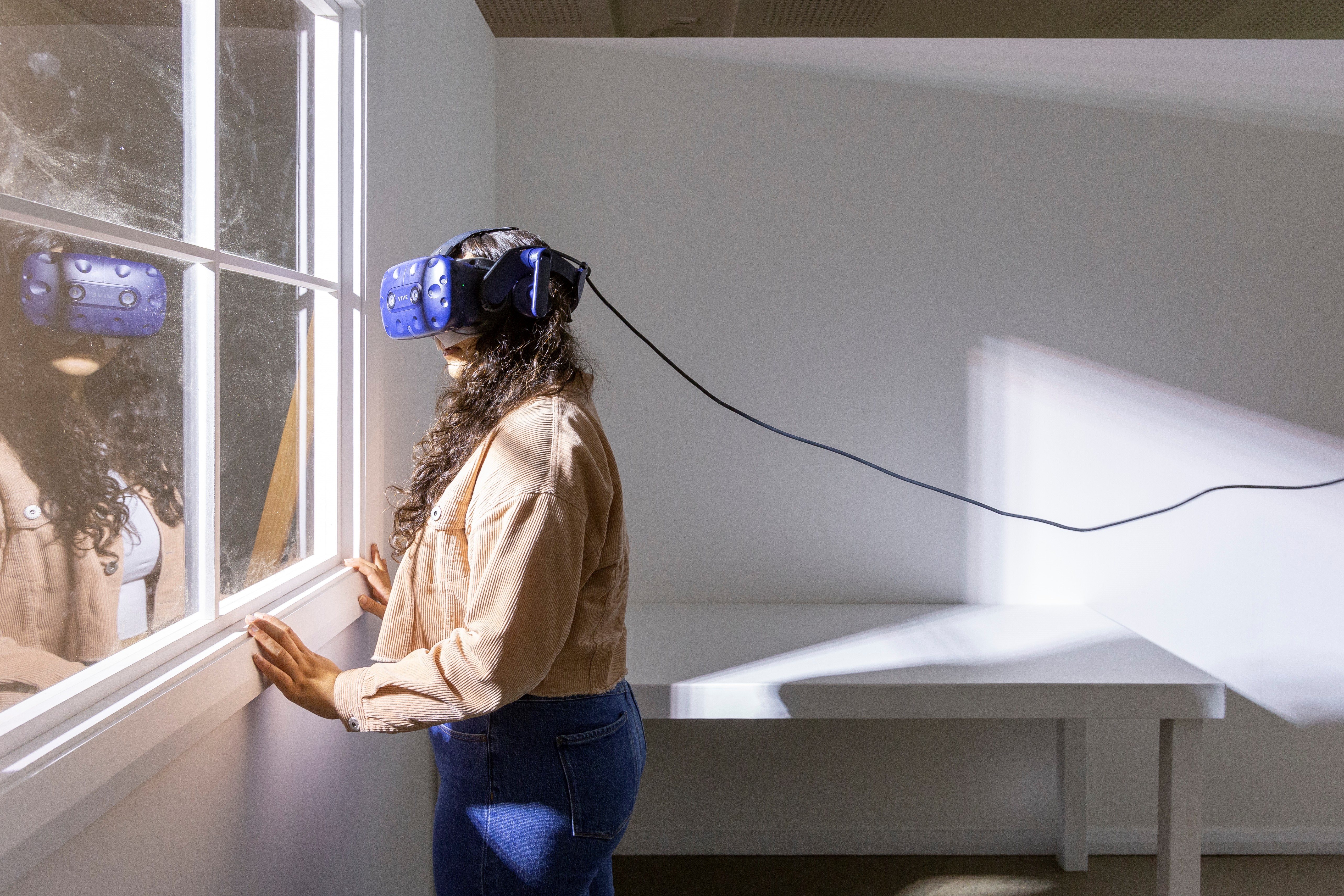 Woman with VR head set stands next to a window