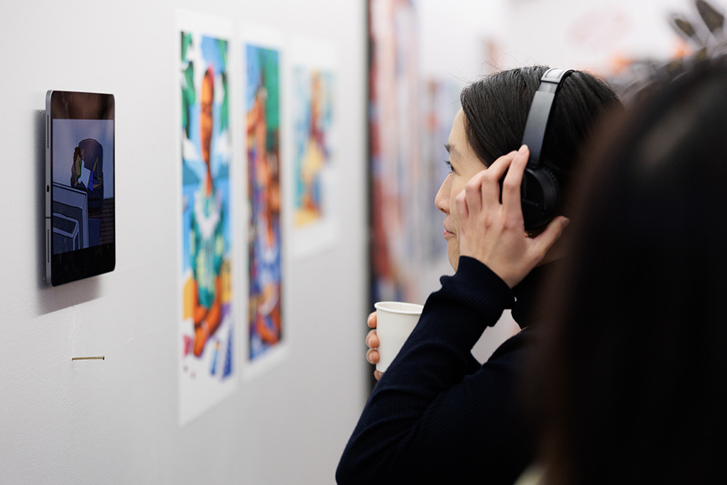 A person with headphones on watching an animation as part of the exhibition 