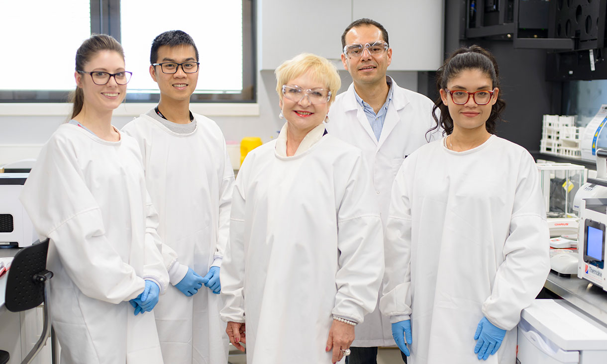 Group photo of researchers in lab wearing white lab coats.