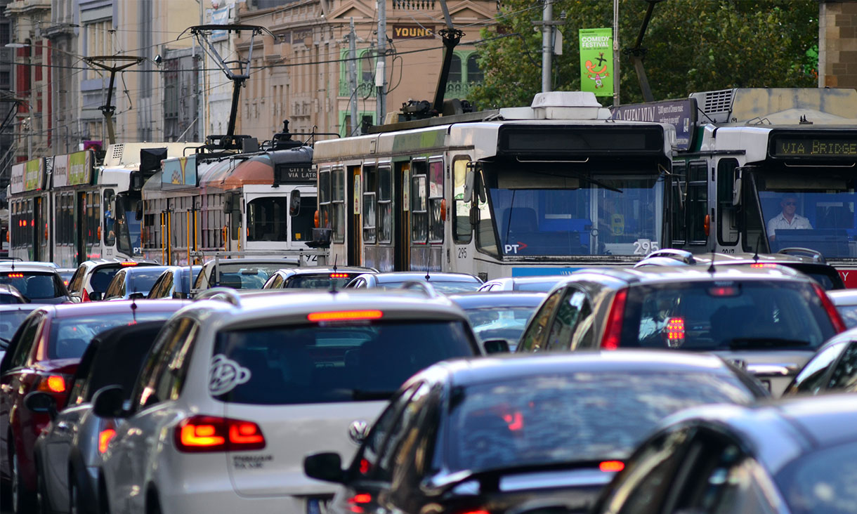 Trams and cars on crowded Melbourne city street.