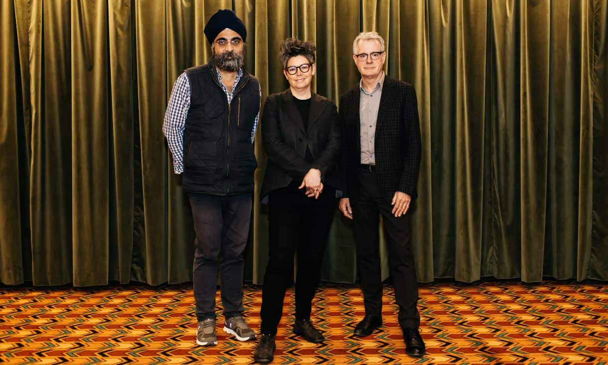 Indy Johar, Naomi Stead and Tim Marshall standing side by side in front of a curtain backdrop
