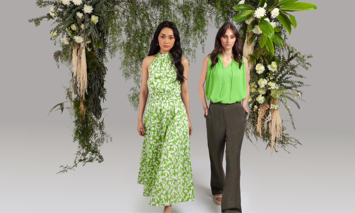 2 female models posing in front of a plant archway