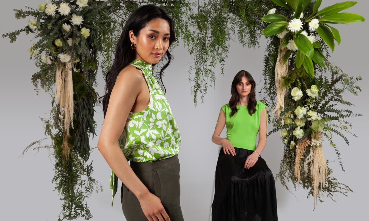 2 female models standing in front of a plant archway