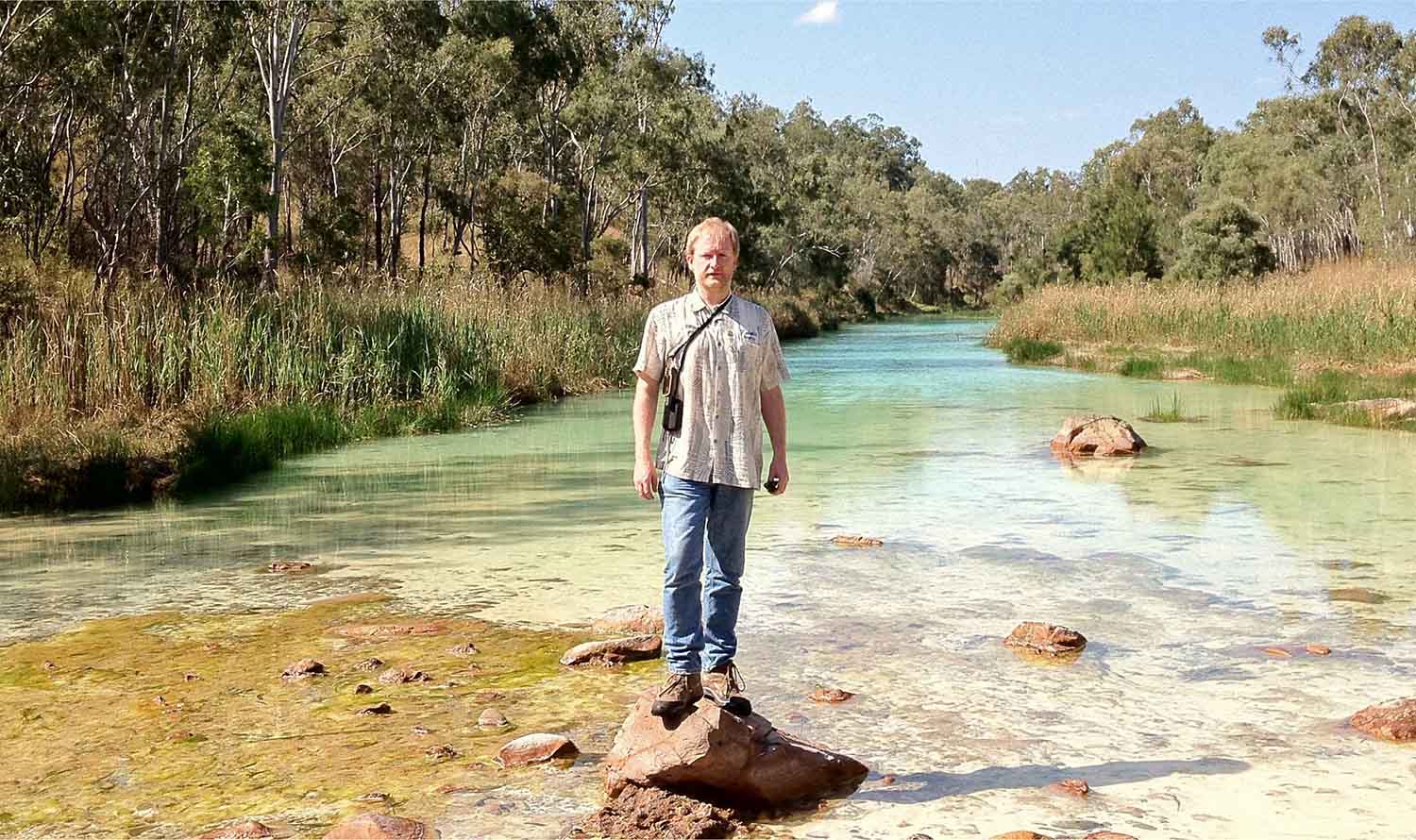 Gavin Mudd standing on a rock in a creek bed