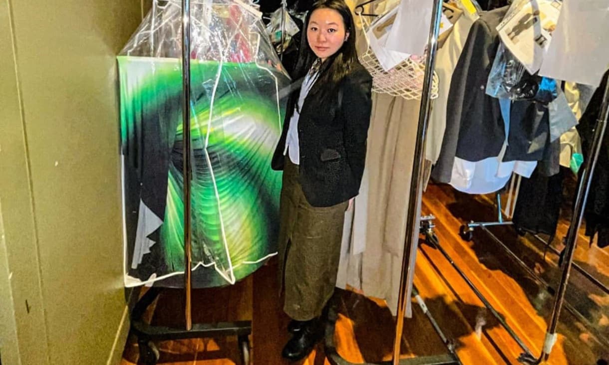 Bei Bei Li stands in front of the clothing she designed.