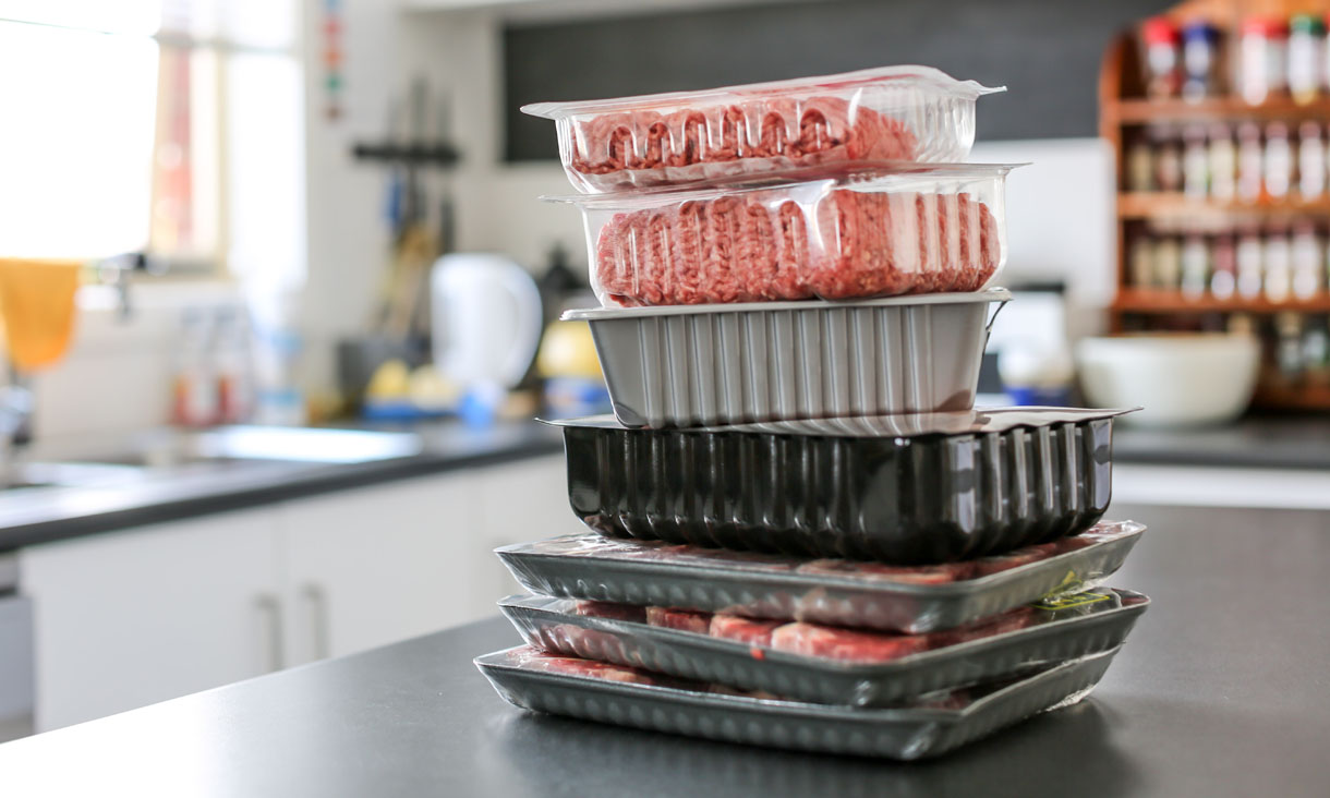 A pile of meat trays stacked on top of each other on a kitchen bench.