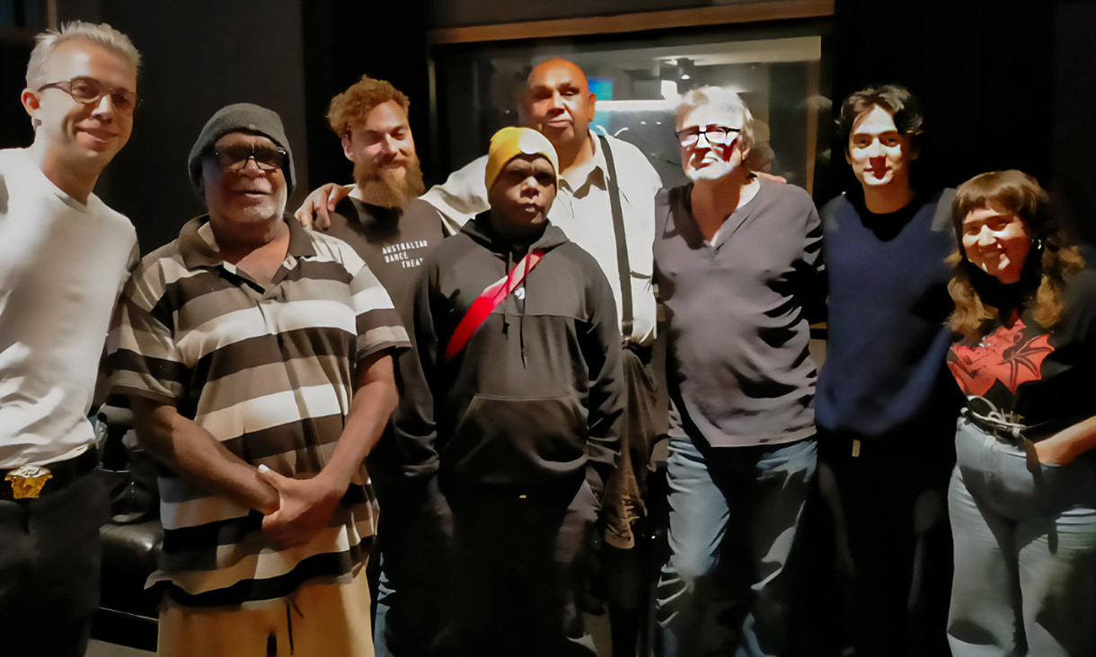 7 men and 1 women stand together in a recording studio