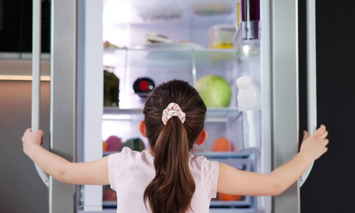 A child opening both doors of the fridge to see what's inside.